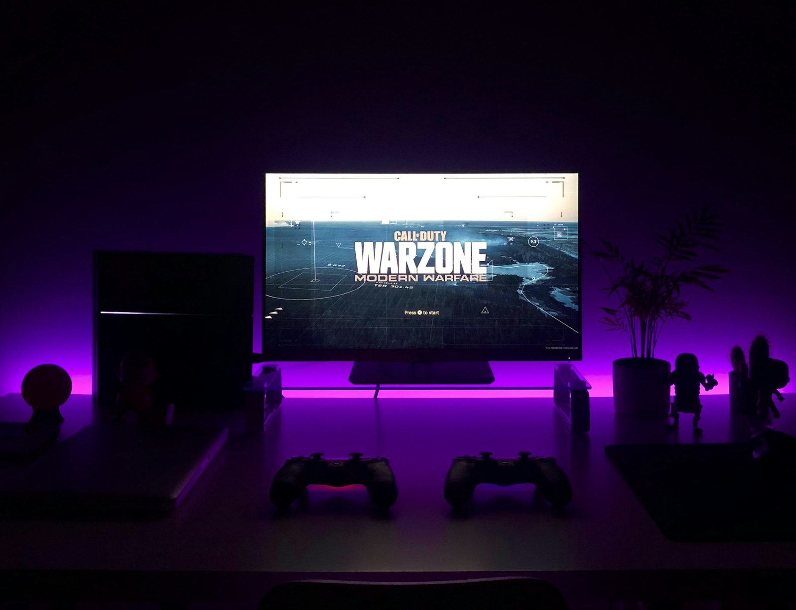 PlayStation console setup on a big screen with controllers under neon light